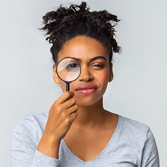 Curious black girl holding magnifier over grey background, panorama with copy space